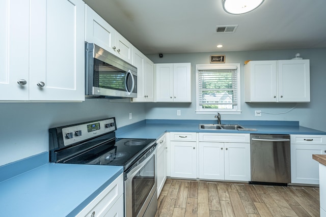 kitchen featuring appliances with stainless steel finishes, light hardwood / wood-style flooring, white cabinets, and sink