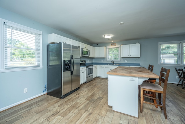 kitchen featuring wooden counters, white cabinets, stainless steel appliances, and a healthy amount of sunlight