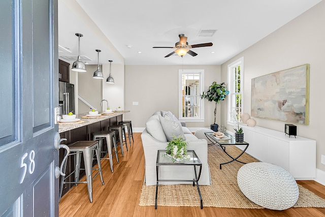 living room featuring light wood-type flooring and ceiling fan