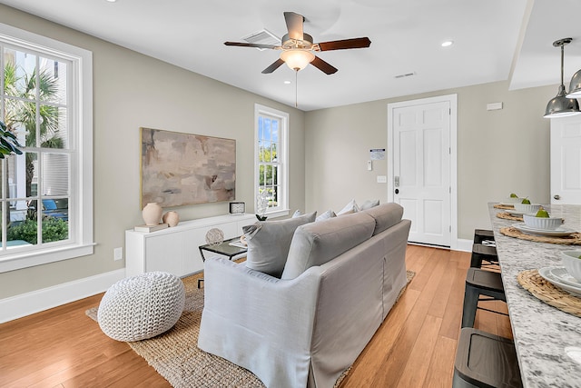 living room featuring a healthy amount of sunlight, ceiling fan, and light hardwood / wood-style flooring