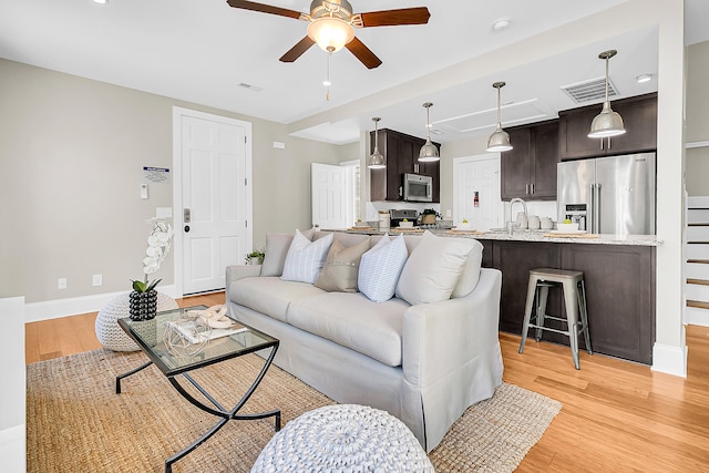 living room featuring ceiling fan, sink, and light hardwood / wood-style flooring