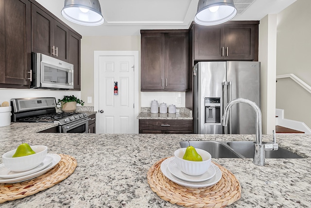 kitchen with light stone counters, sink, appliances with stainless steel finishes, and dark brown cabinets