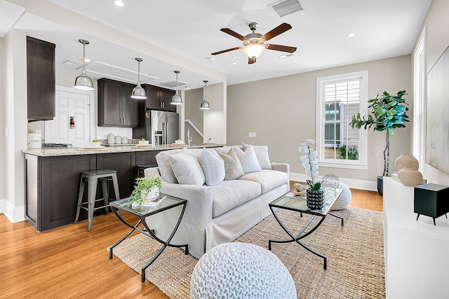 living room with light hardwood / wood-style flooring and ceiling fan