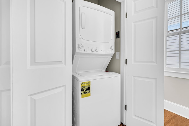 clothes washing area with light hardwood / wood-style flooring and stacked washer and clothes dryer