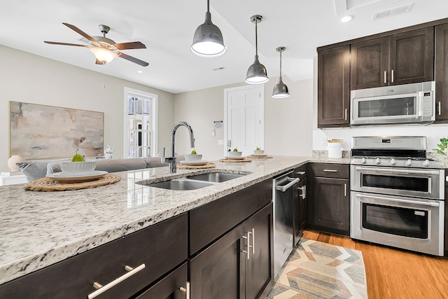 kitchen with decorative light fixtures, appliances with stainless steel finishes, sink, ceiling fan, and light wood-type flooring