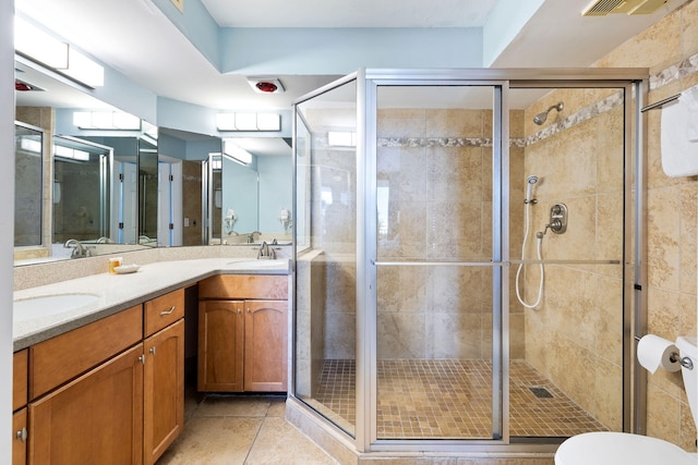 bathroom with double vanity, a stall shower, a sink, and tile patterned flooring