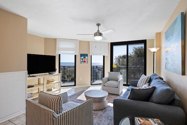 tiled living area with a wall of windows and a ceiling fan