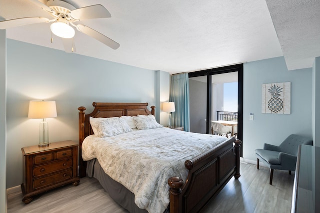 bedroom with light wood finished floors, a textured ceiling, baseboards, and access to exterior