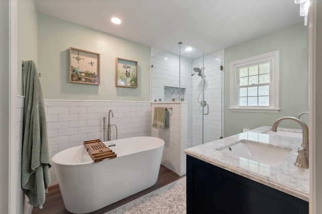 44 S Basilica Ave, Hanahan, SC 29410 - full bathroom with tile walls, wood finished floors, tiled shower, vanity, and a soaking tub