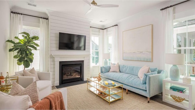 living room featuring a fireplace, ceiling fan, and plenty of natural light