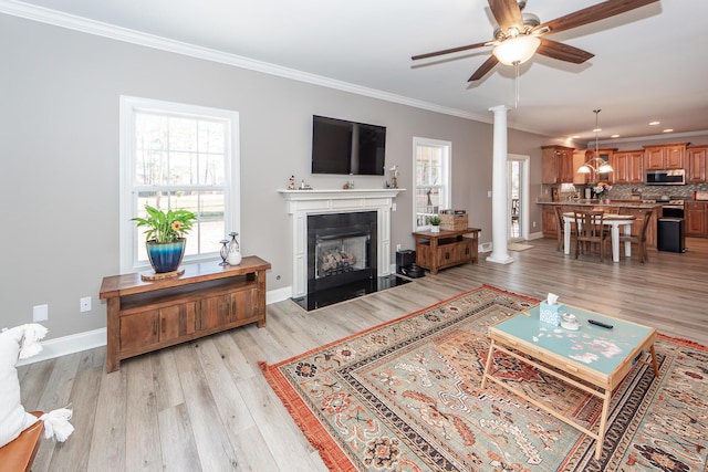 living room featuring crown molding, plenty of natural light, light wood-style floors, and decorative columns