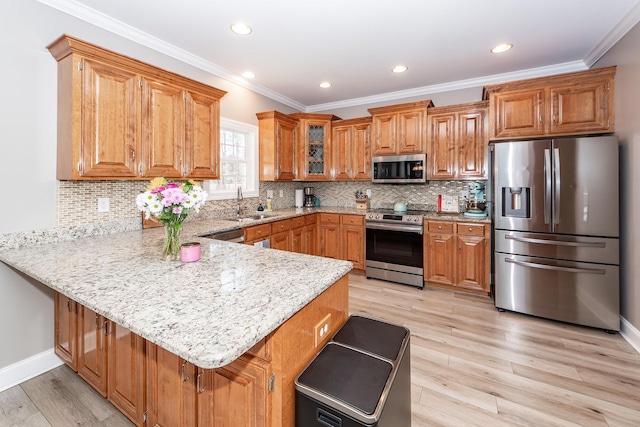 kitchen with a breakfast bar area, light wood-style flooring, a peninsula, brown cabinetry, and stainless steel appliances