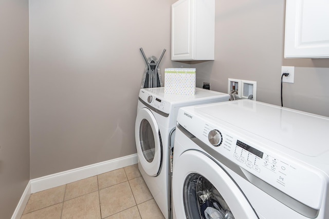 clothes washing area featuring light tile patterned floors, cabinet space, baseboards, and washing machine and clothes dryer