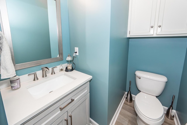 bathroom featuring toilet, vanity, baseboards, and wood finished floors