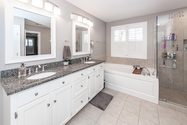 full bathroom featuring a garden tub, double vanity, a sink, a shower stall, and tile patterned floors