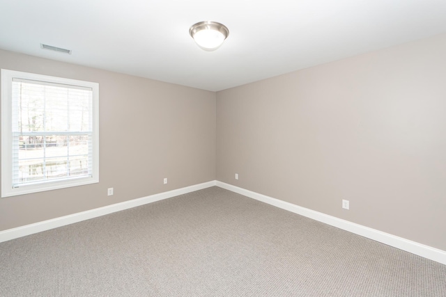 carpeted spare room featuring baseboards and visible vents