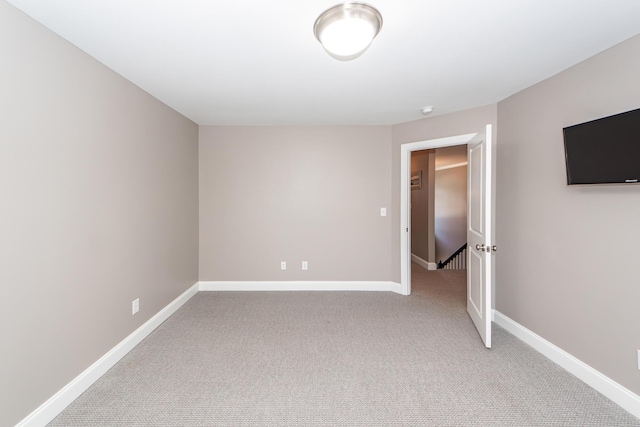 unfurnished room with baseboards and light carpet