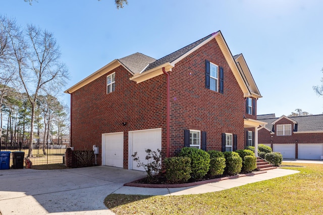 view of property exterior featuring a garage, fence, brick siding, and driveway