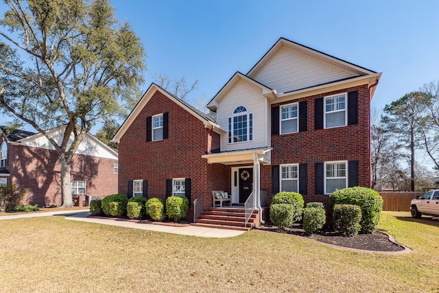 view of front of property with a front lawn, fence, and brick siding