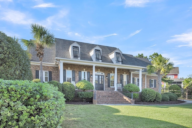 cape cod-style house featuring a front lawn, french doors, brick siding, a shingled roof, and covered porch
