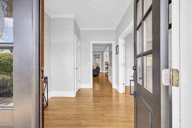 foyer entrance with healthy amount of natural light, light wood-style floors, ornamental molding, and baseboards