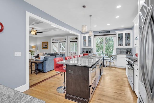 kitchen with stainless steel appliances, a breakfast bar, white cabinets, and recessed lighting