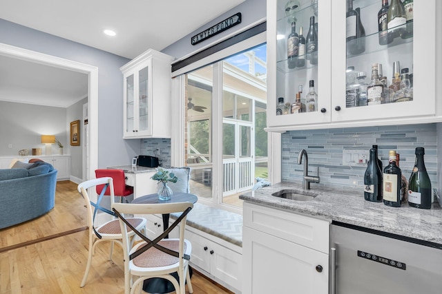 indoor wet bar featuring stainless steel dishwasher, backsplash, plenty of natural light, light wood-type flooring, and recessed lighting