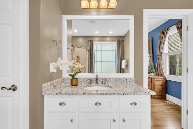 bathroom with a stall shower, vanity, baseboards, and wood finished floors