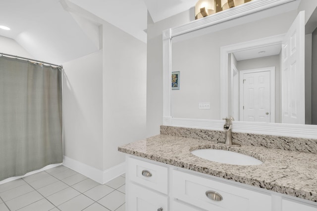 full bath featuring vanity, tile patterned flooring, baseboards, and vaulted ceiling
