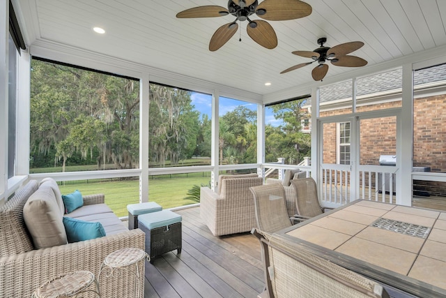 sunroom / solarium featuring ceiling fan and view of wooded area
