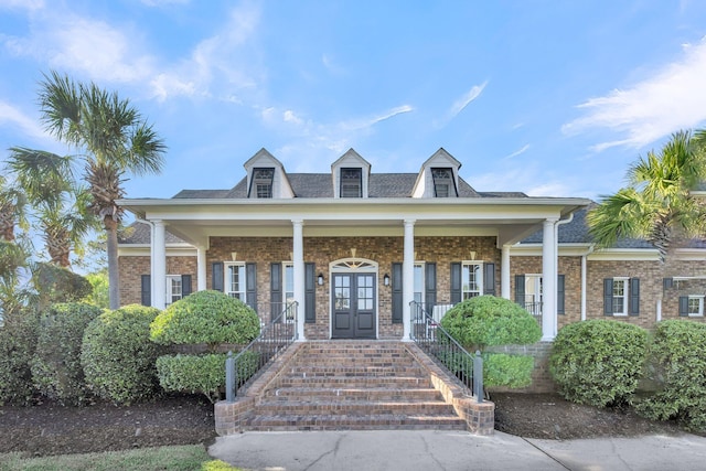view of front of house featuring french doors, a porch, stairs, and brick siding