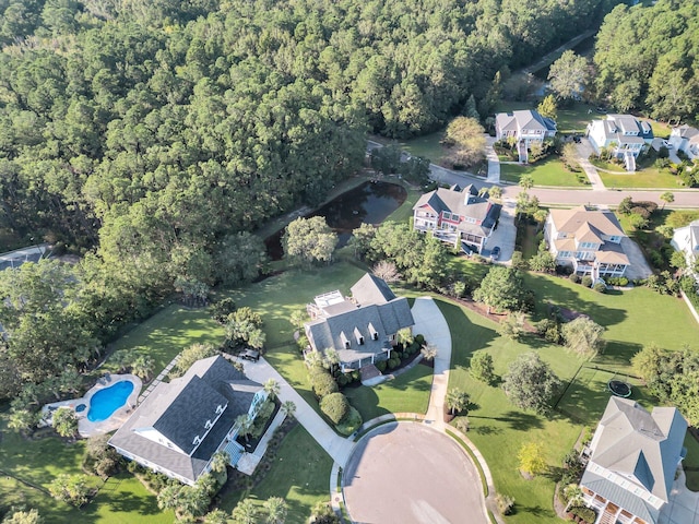 aerial view of property and surrounding area featuring a heavily wooded area, nearby suburban area, and a pool area