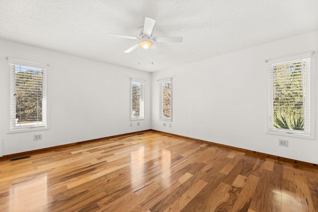 empty room with ceiling fan, wood-type flooring, and a textured ceiling