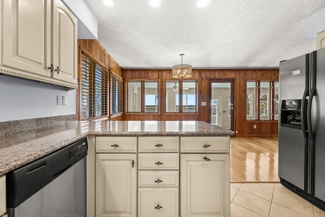 kitchen featuring cream cabinets, stainless steel appliances, and wood walls