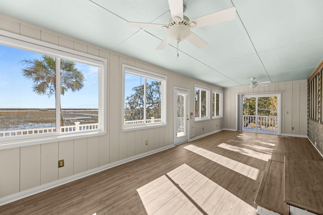 unfurnished sunroom with ceiling fan, a water view, and a healthy amount of sunlight