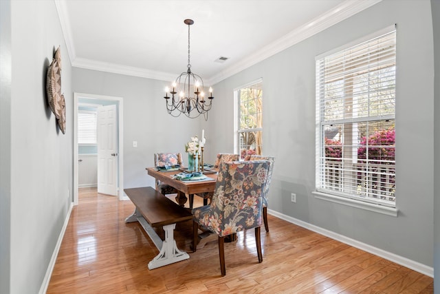 dining space with light wood-type flooring, an inviting chandelier, and ornamental molding