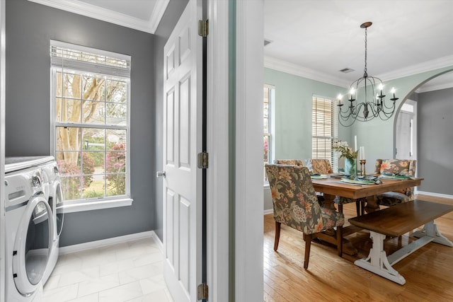 dining area with baseboards, an inviting chandelier, separate washer and dryer, arched walkways, and crown molding