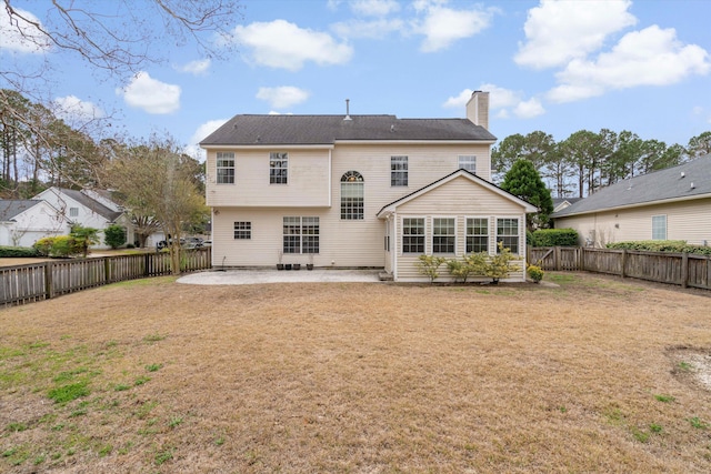 rear view of house featuring a patio, a lawn, a fenced backyard, and a chimney