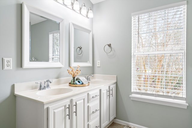 full bath featuring double vanity, a healthy amount of sunlight, and a sink