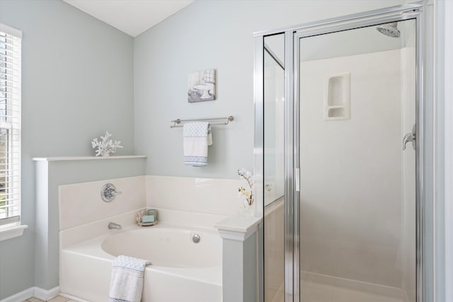 full bathroom featuring baseboards, a bath, and a shower stall