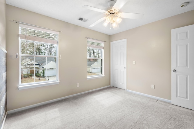 unfurnished room featuring visible vents, baseboards, light colored carpet, and a ceiling fan