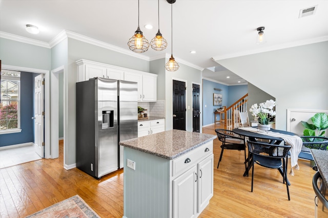 kitchen featuring visible vents, backsplash, white cabinets, stainless steel fridge with ice dispenser, and light wood finished floors