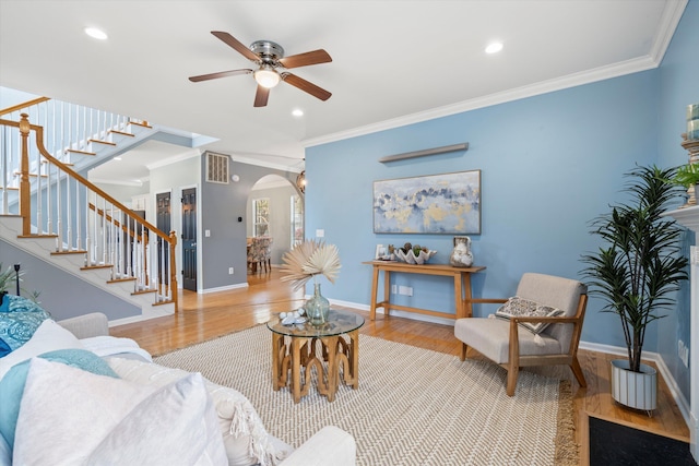 living area with visible vents, wood finished floors, stairway, arched walkways, and crown molding