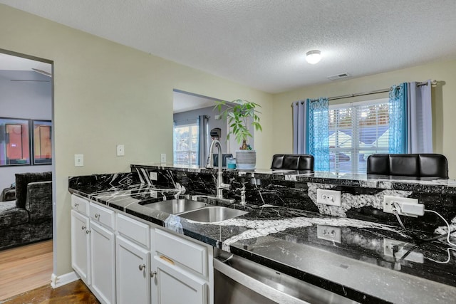 kitchen featuring wood-type flooring, sink, white cabinetry, a textured ceiling, and dishwashing machine