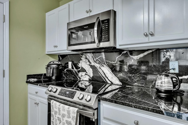 kitchen with stainless steel appliances, dark stone countertops, white cabinets, and tasteful backsplash