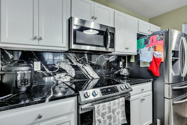 kitchen featuring a textured ceiling, appliances with stainless steel finishes, backsplash, and white cabinets