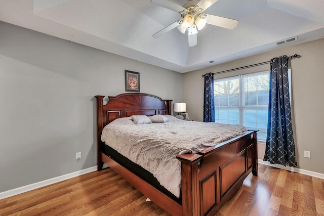 bedroom featuring a raised ceiling, ceiling fan, and light hardwood / wood-style floors