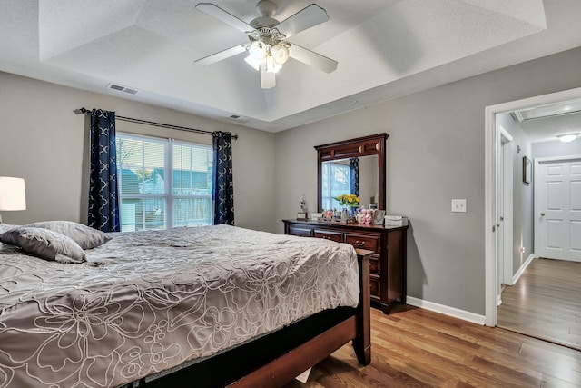 bedroom featuring ceiling fan, a tray ceiling, and hardwood / wood-style flooring