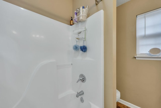 bathroom with shower / bathtub combination, a textured ceiling, and toilet