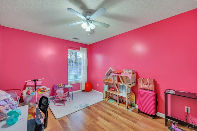 playroom with a textured ceiling, ceiling fan, and hardwood / wood-style floors